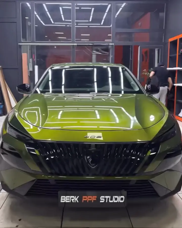 Komple PPF kaplaması bitmiş yeşil Peugeot 408, önünde Berk PPF Studio plakası